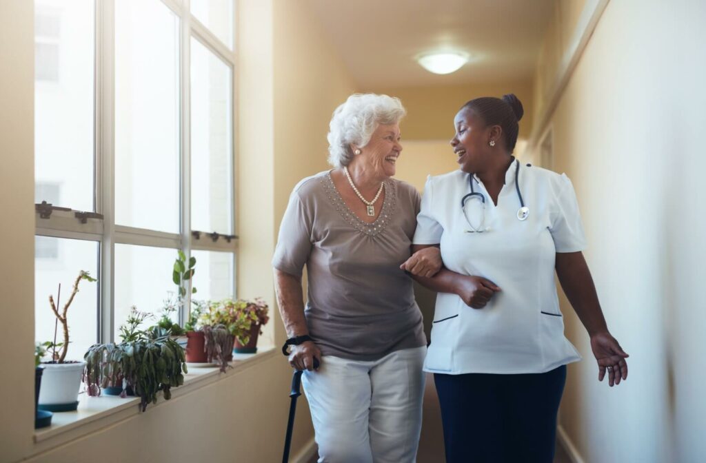 A caregiver walking with a senior woman while smiling away