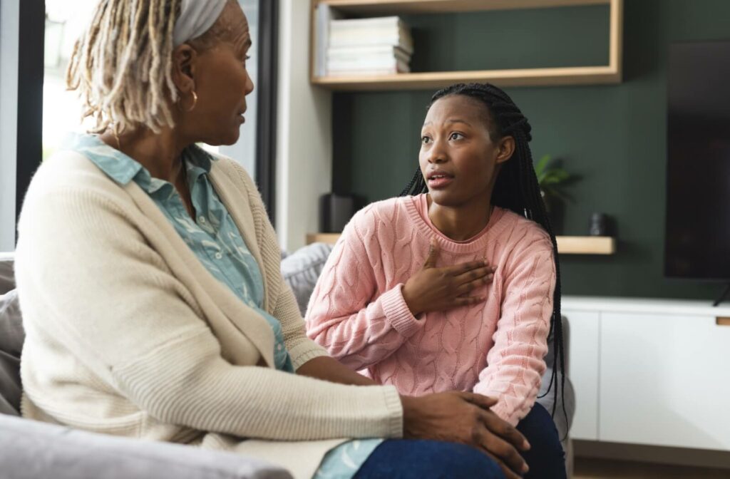 An adult sits their older parent on the couch to have an open, heart-to-heart conversation about memory care